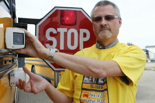 man showing camera on side of school bus