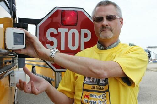 man showing camera on side of school bus