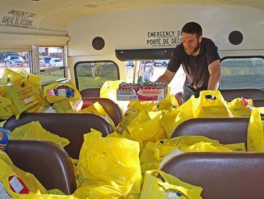 Teacher Kendell Wiens helps load up a bus as part of Kate Andrews High School's annual Community Food Drive.