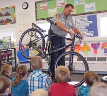 School resource officer Jerry Gurr shows some bike safety skills off to students at John Davidson School during Safety Day.