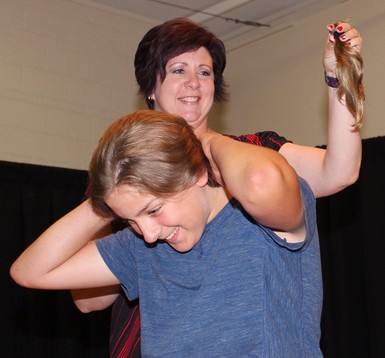 Wendi Smith holds up the newly snipped ponytail while Champion School student Brody Delude experiences his first haircut in more than a year.