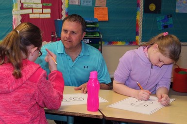 Principal Fred Jack works with some Barons School students on their legacy books.